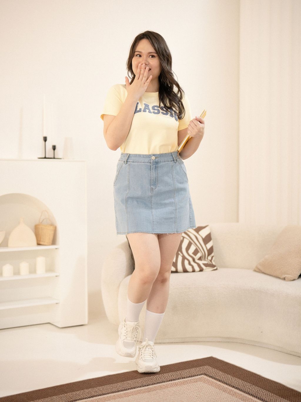 Plus-size model smiling in yellow CLASSIC tee and Fray Line Denim Mini.