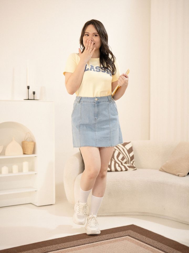 Plus-size model smiling in yellow CLASSIC tee and Fray Line Denim Mini.
