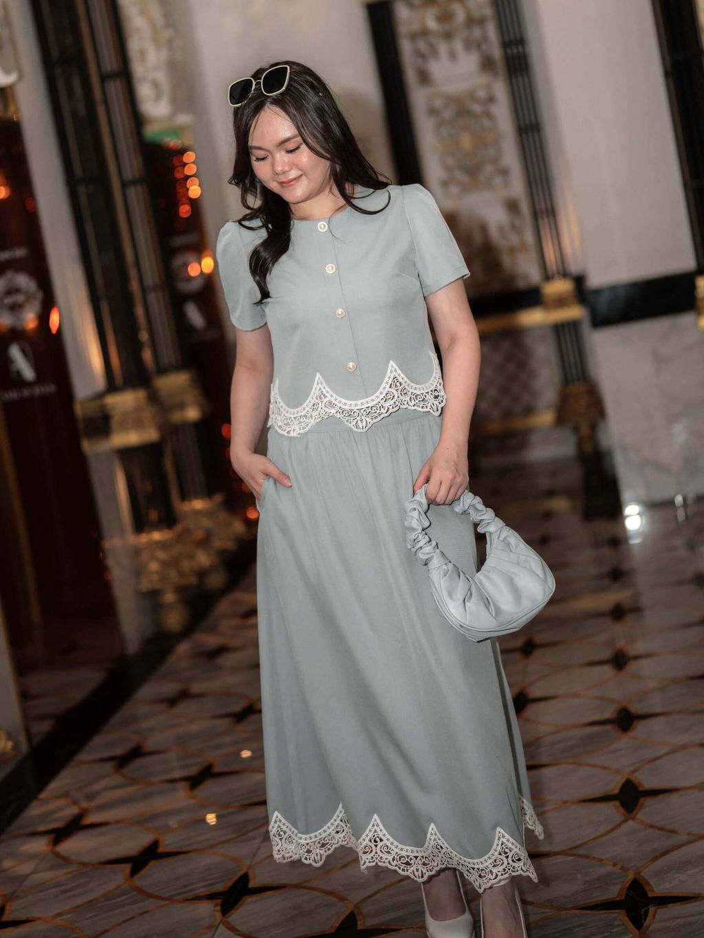 Graceful lace details accent the hem of the blue midi skirt and matching top as the model walks.