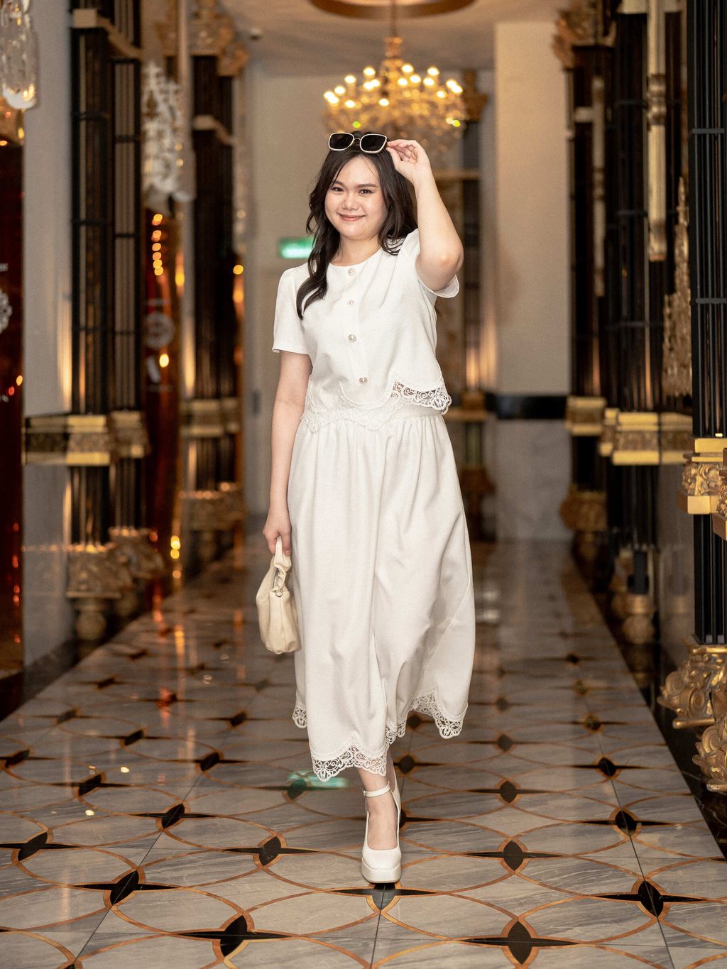 Radiant plus-size woman adjusting sunglasses while dressed in a white lace scallop set.