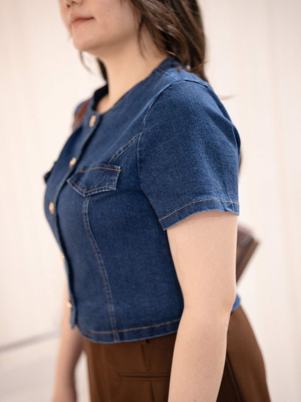 Side view of short sleeve denim jacket with gold buttons