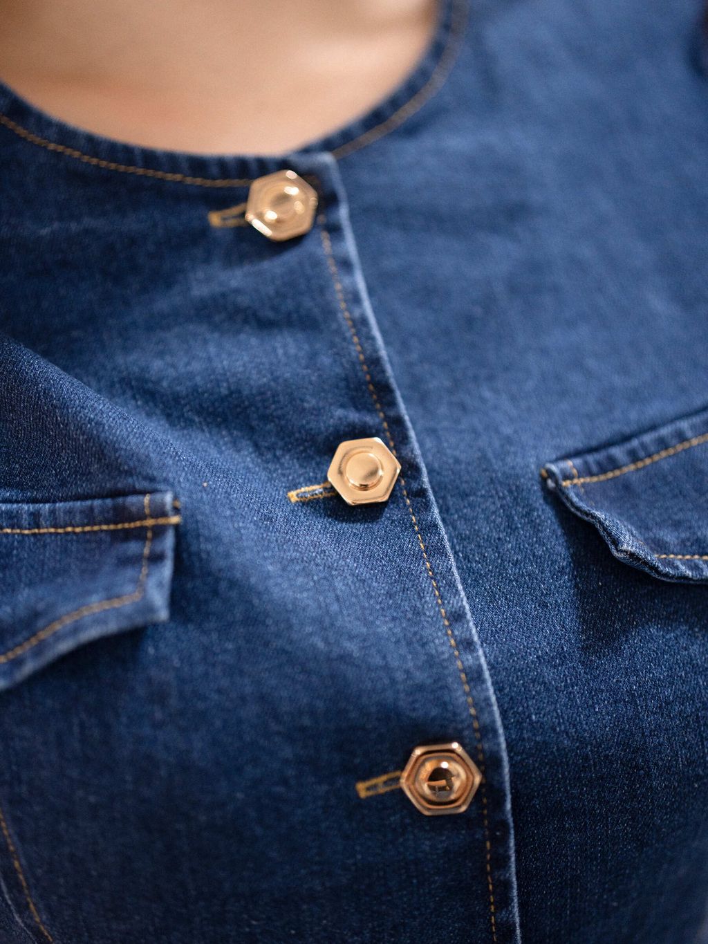 Close-up of hexagon gold buttons on denim top