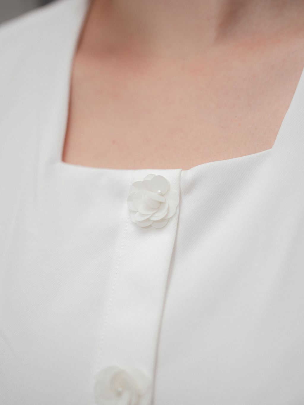 Close-up of camellia-inspired pearl buttons on the blouse.