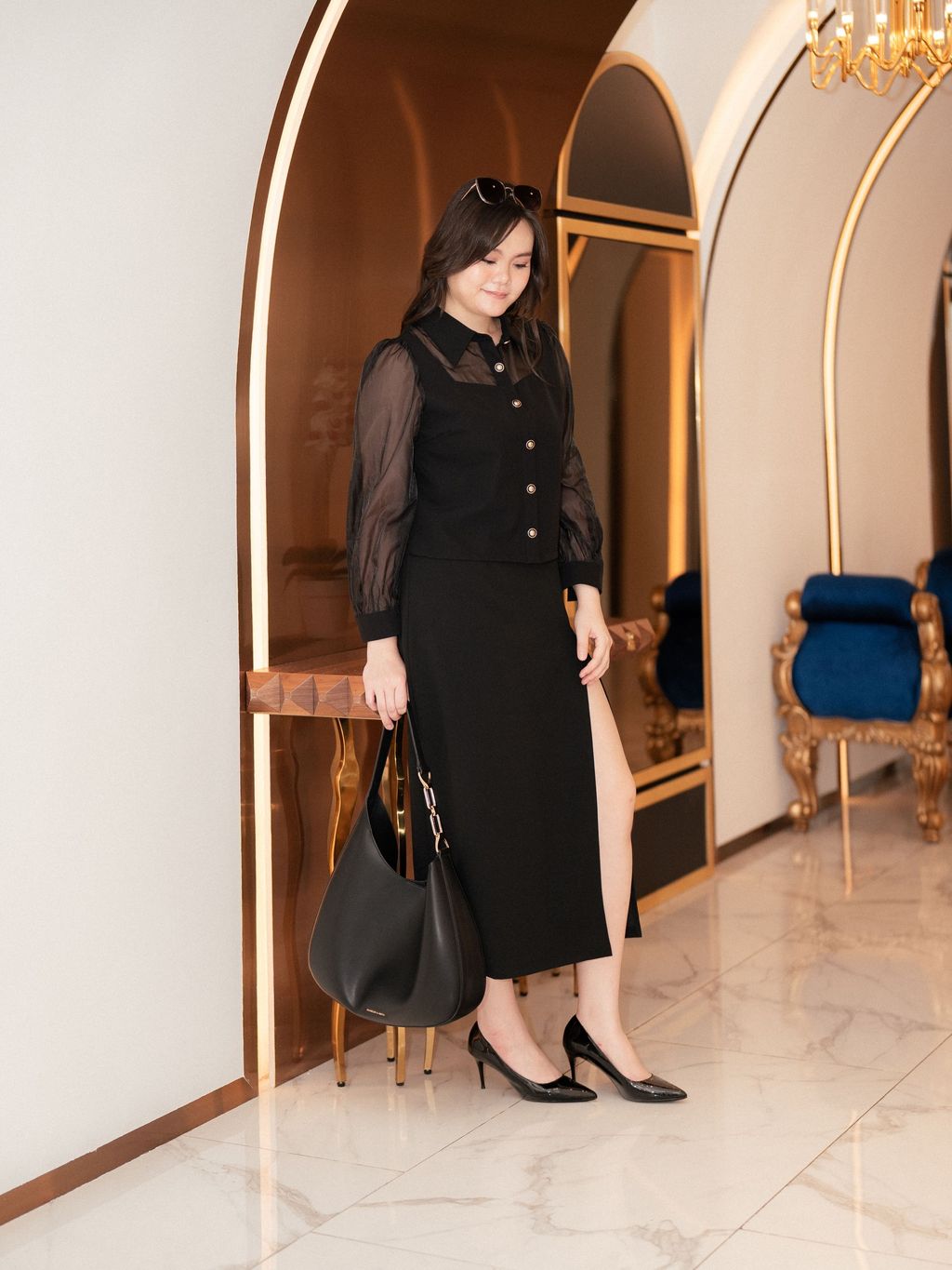 Plus-size woman wearing sheer long sleeve blouse with gold buttons.