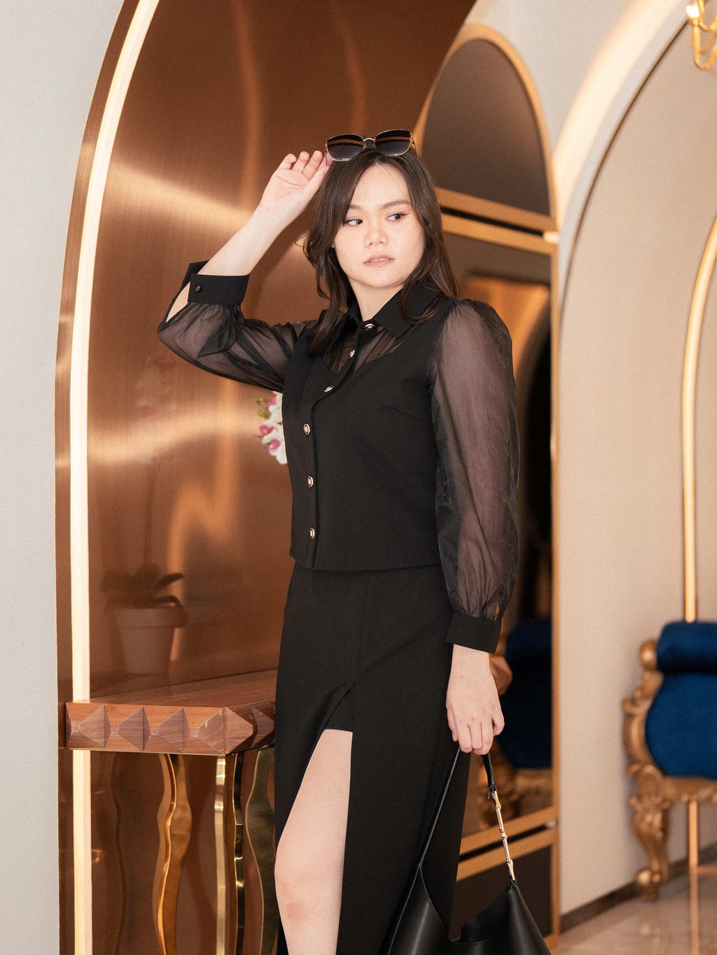 Stylish sheer-sleeve blouse styled with pointed heels and a leather bag.