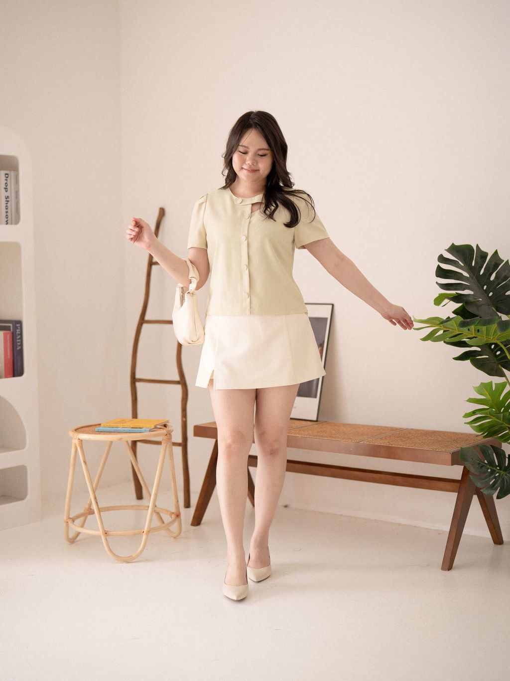 Plus-size woman walking in a minimal room wearing floral button chic top and white skirt.