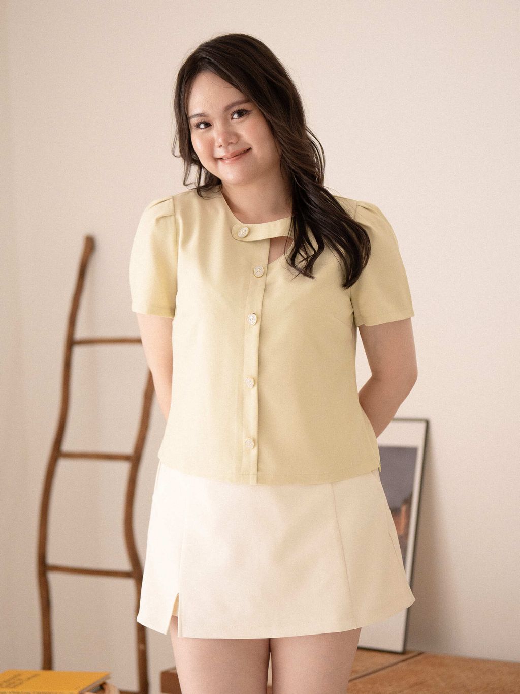 Woman posing with hands behind her back in floral pearl button top.