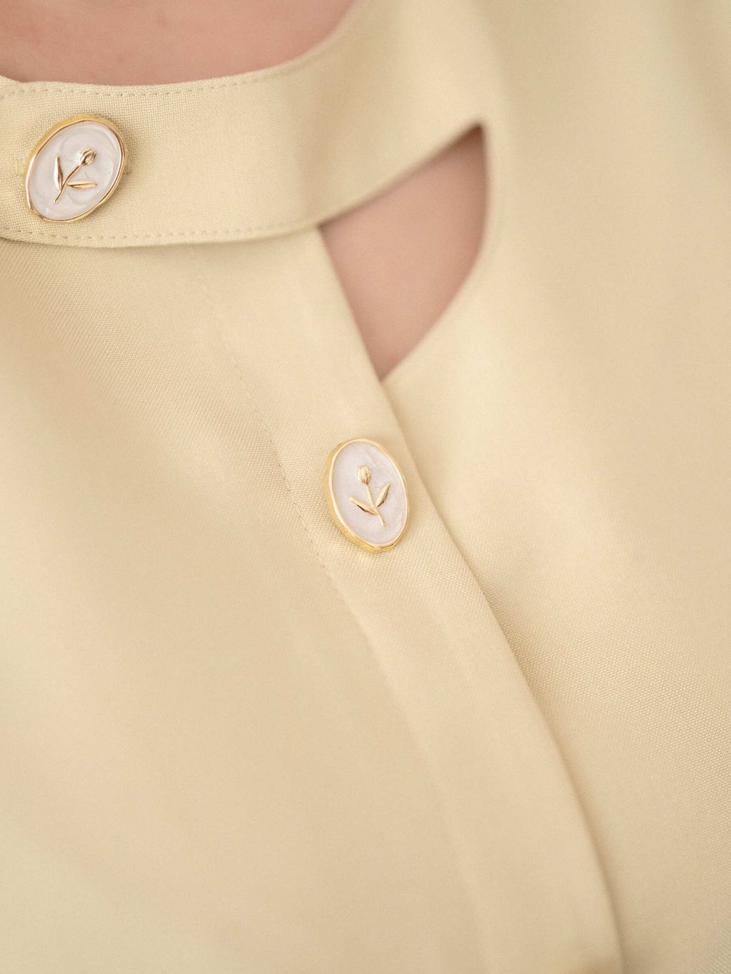 Macro close-up of the gold-trimmed floral pearl buttons on collar.