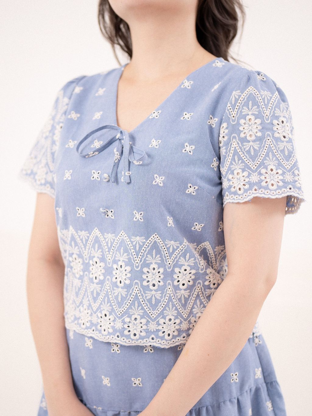 Close-up of floral eyelet embroidery and neckline bow tie.