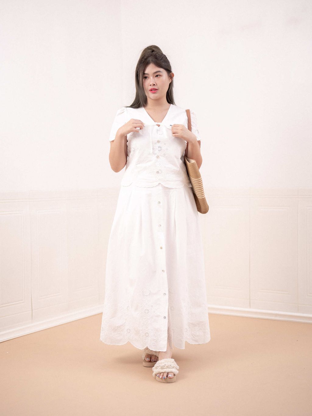 Plus-size model wearing a white embroidered eyelet top with ribbon tie.