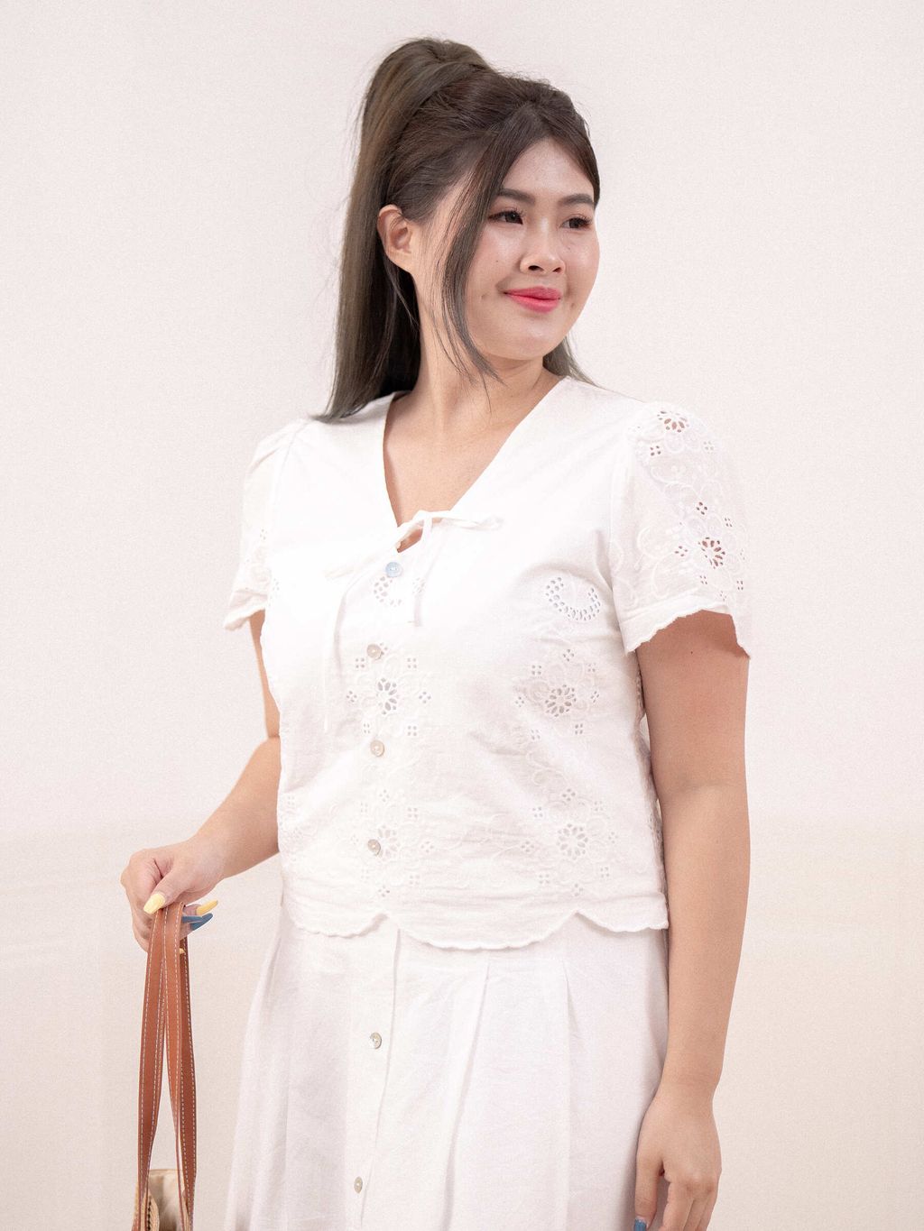 Feminine V-neck top with delicate floral lace details and scalloped hem.