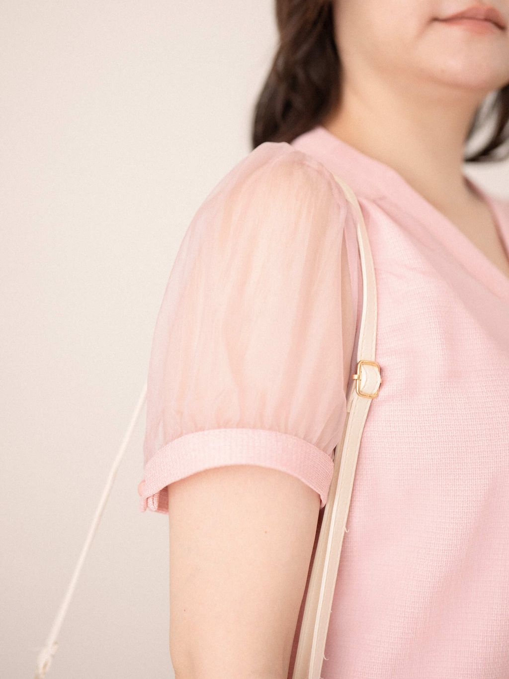 Side view of pink top showing sleeve texture and structured hemline.