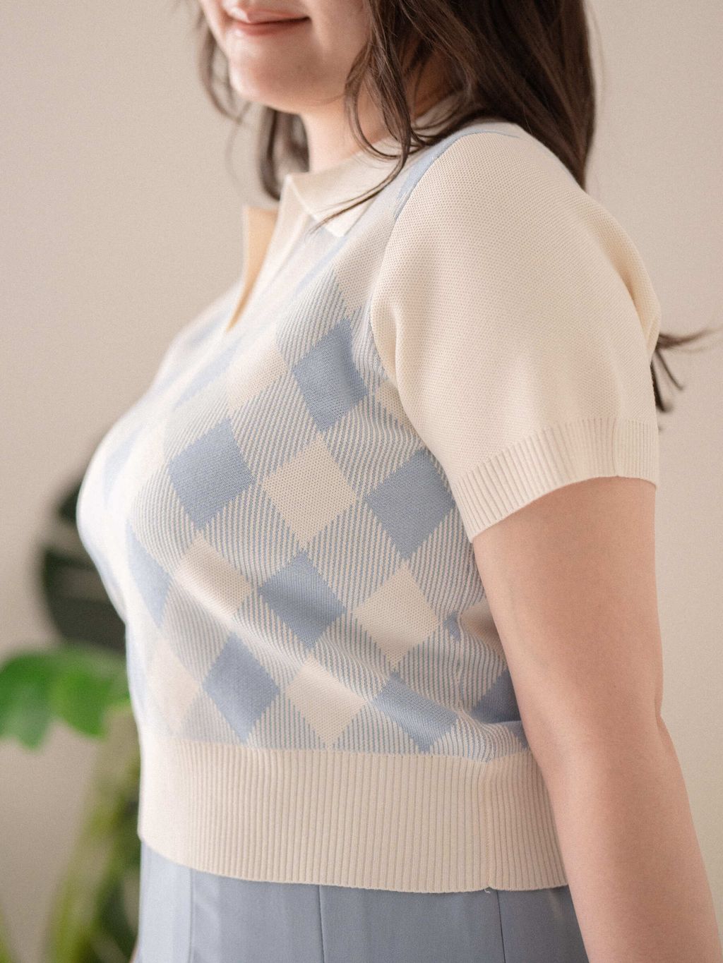 Close-up of pastel blue argyle knit texture with short sleeves and collar.