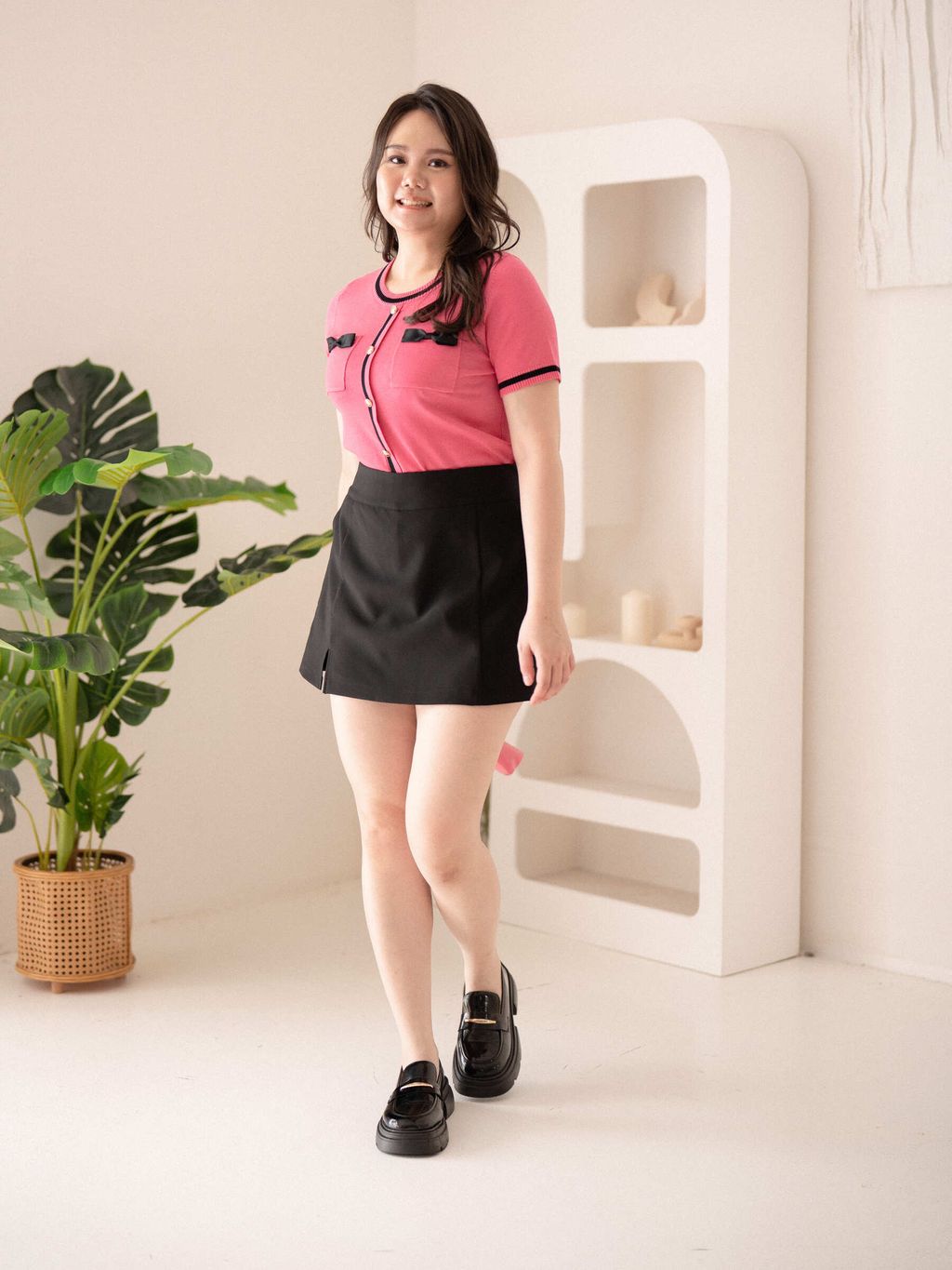 Confident plus-size look with pink short-sleeved knit top and structured silhouette.