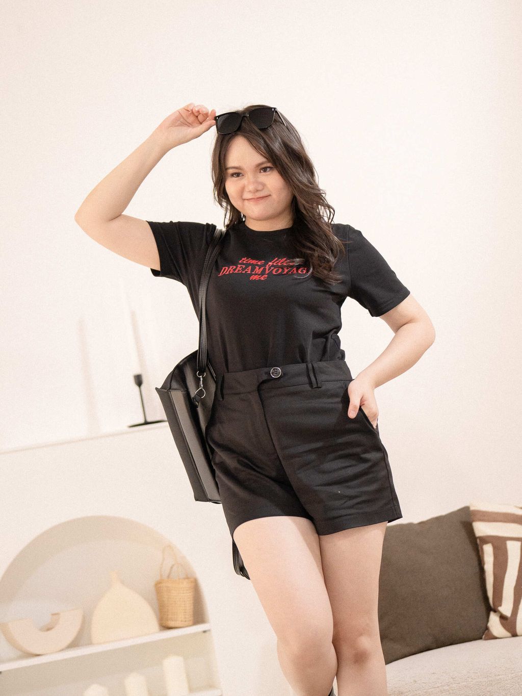 Plus size model in black Dream Voyage Tee and black shorts, styled with boots and sunglasses.