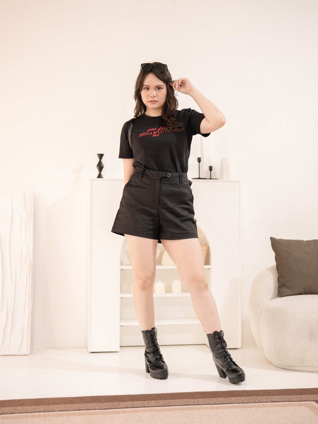 Model in a black Dream Voyage Tee featuring bold red text, paired with high-waisted black shorts and lace-up platform boots for a bold, casual look.