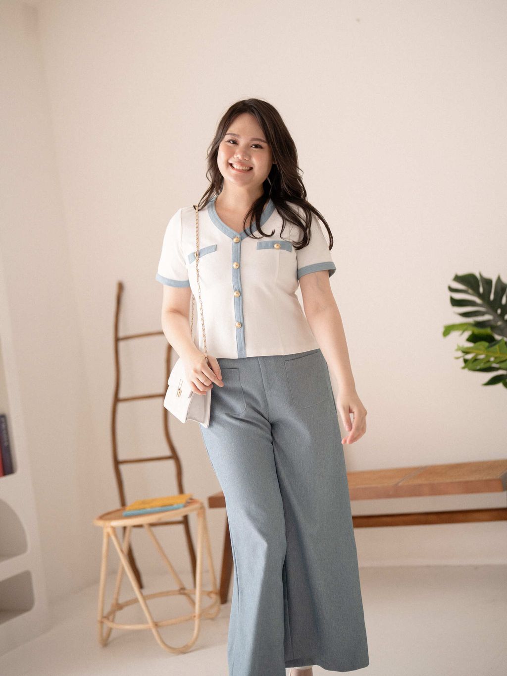 Plus-size model wearing Parisian Trimmed Button Top with denim-trimmed neckline and soft blue pants.