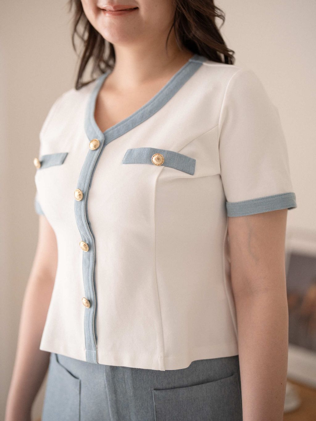 Close-up of chest area showing gold button detail and mock flap pockets on the Parisian Trimmed Top.