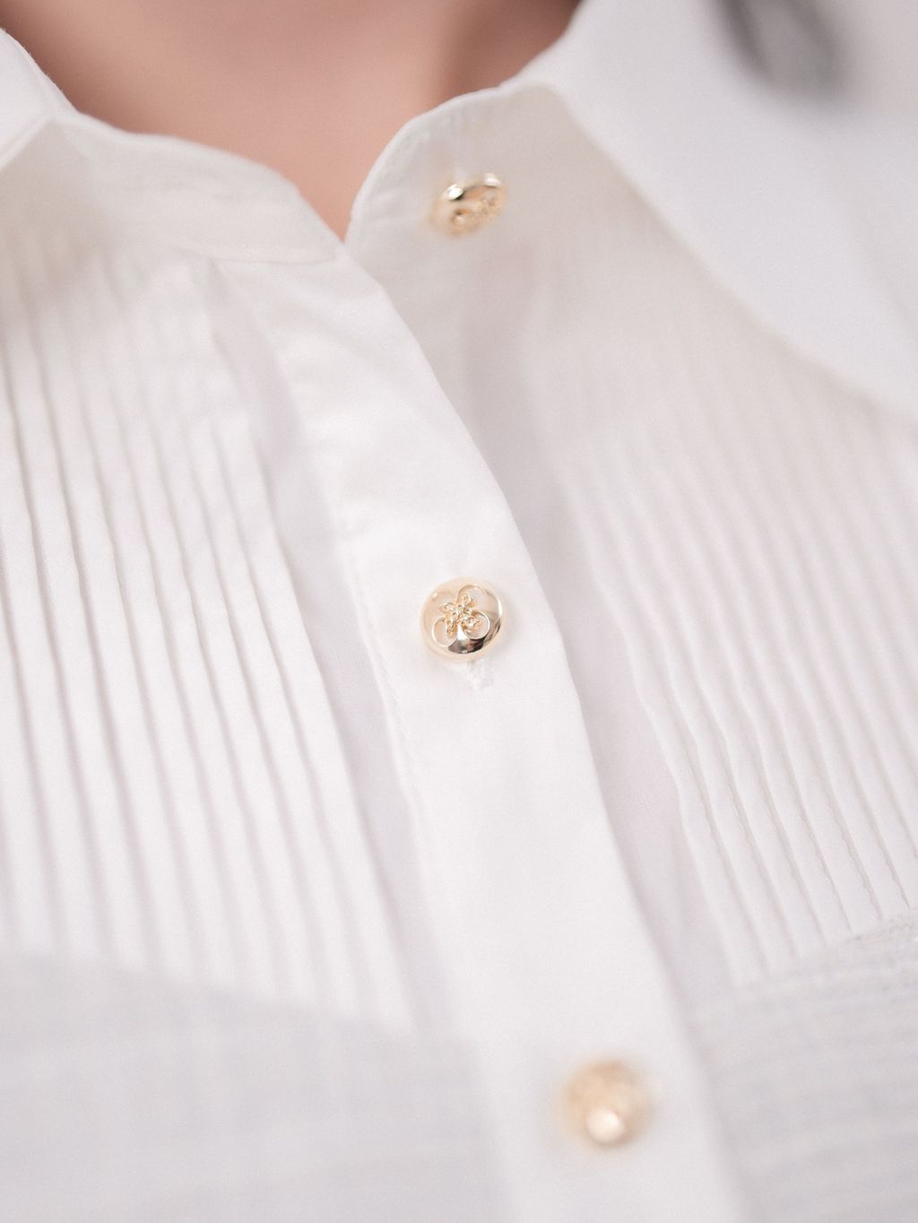 Vertical pleated panel detail on white short-sleeve top.