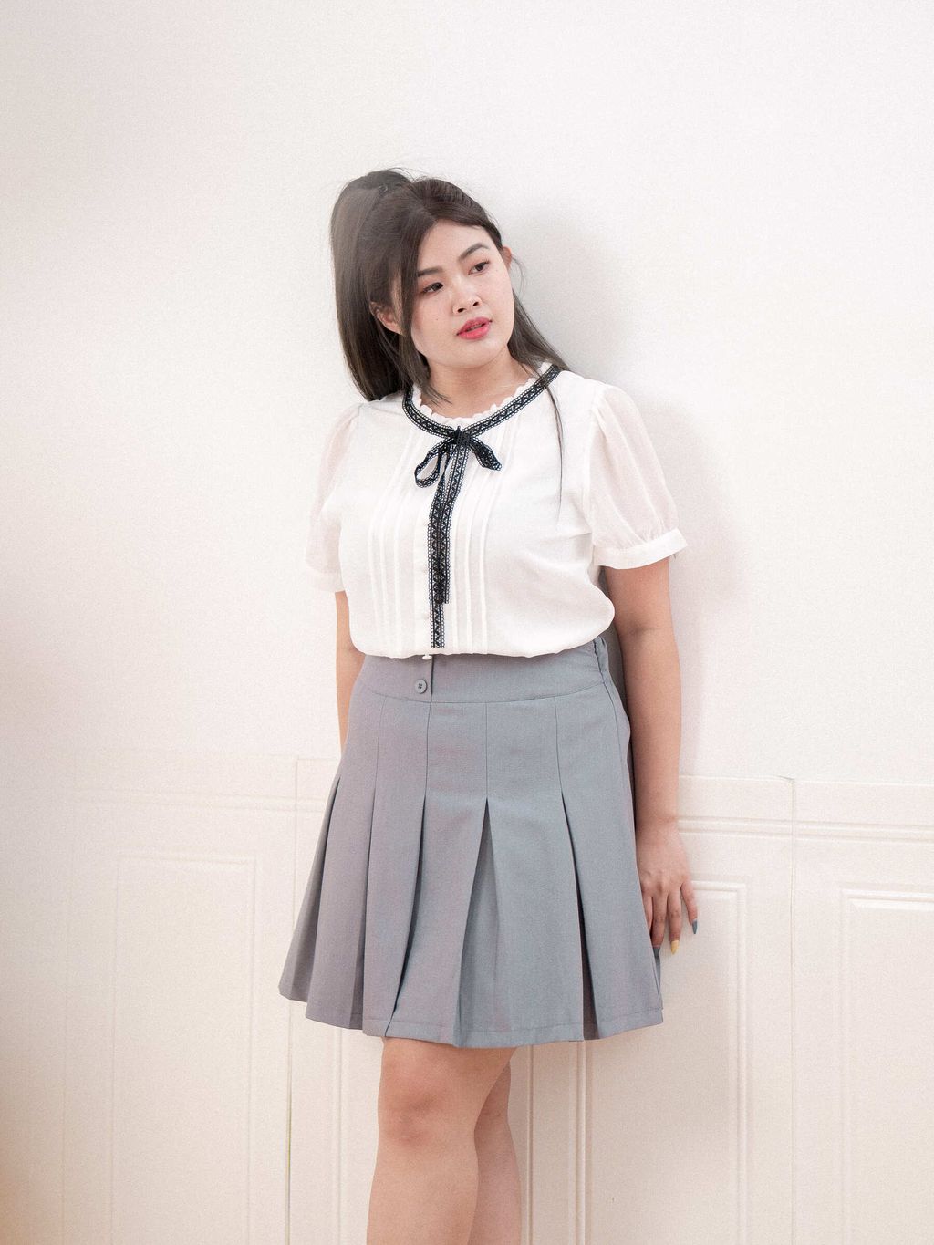 Plus size woman wearing white pleated blouse with black lace ribbon and puff sleeves