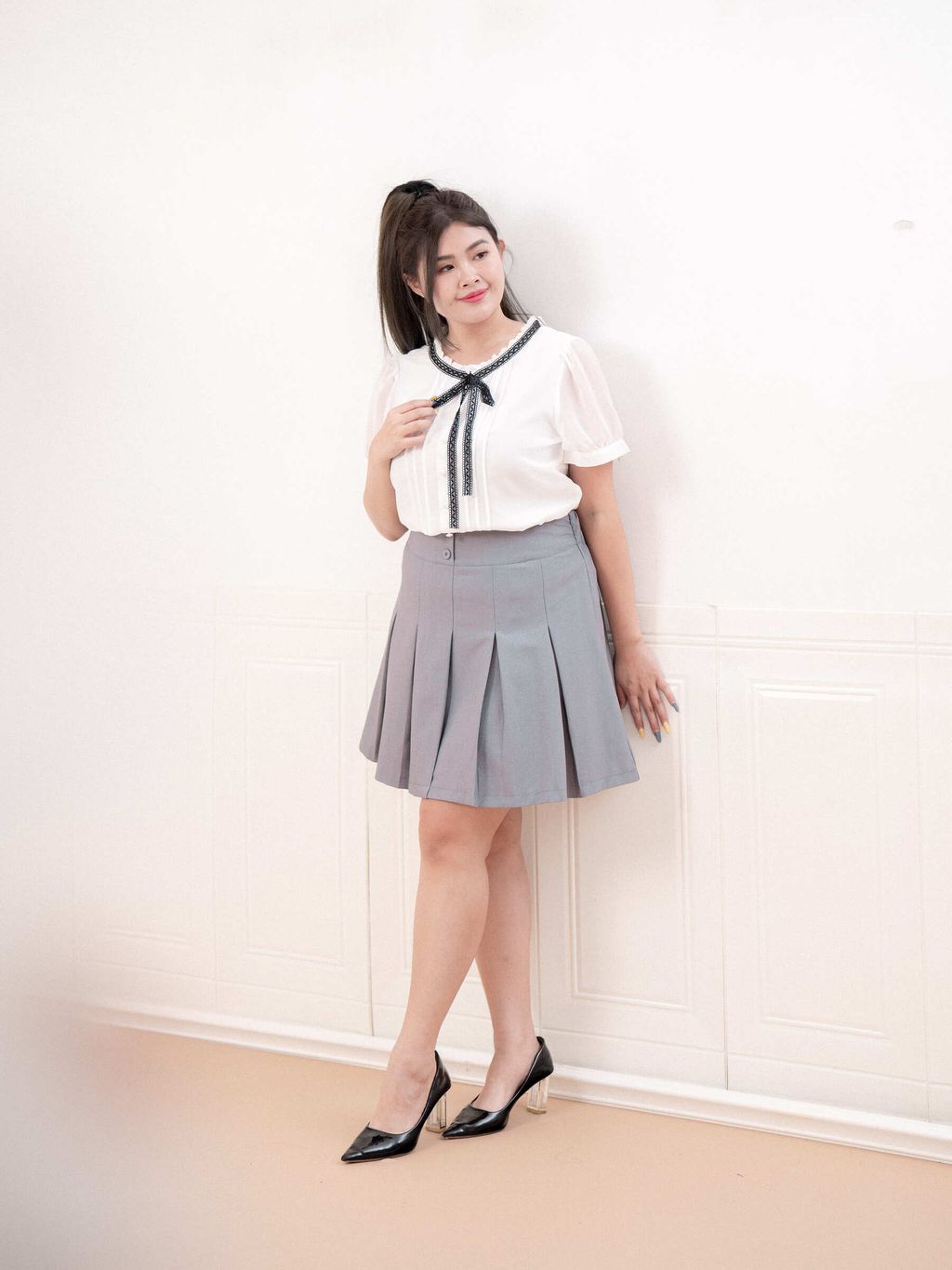 Elegant outfit with white blouse and grey pleated mini skirt