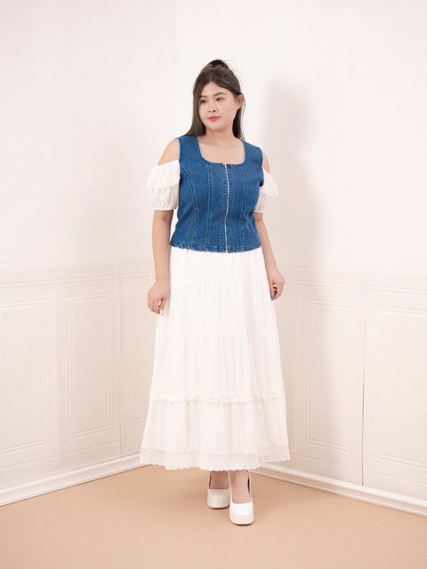Front view of denim top styled over puff-sleeve white dress