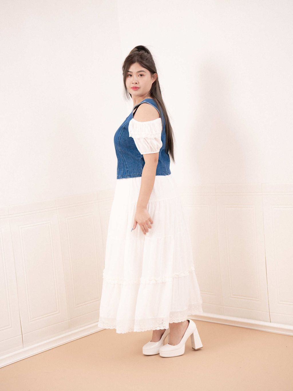 Model posing in denim square-neck top and lace-trimmed white maxi dress