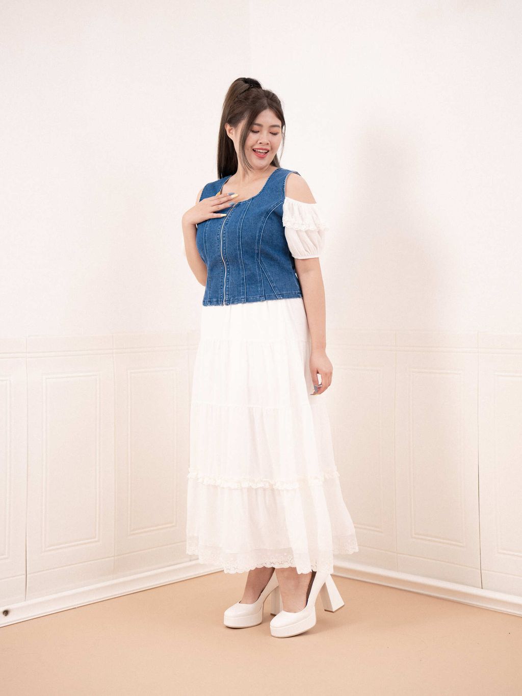 Model smiling in denim zip top with open shoulder detail