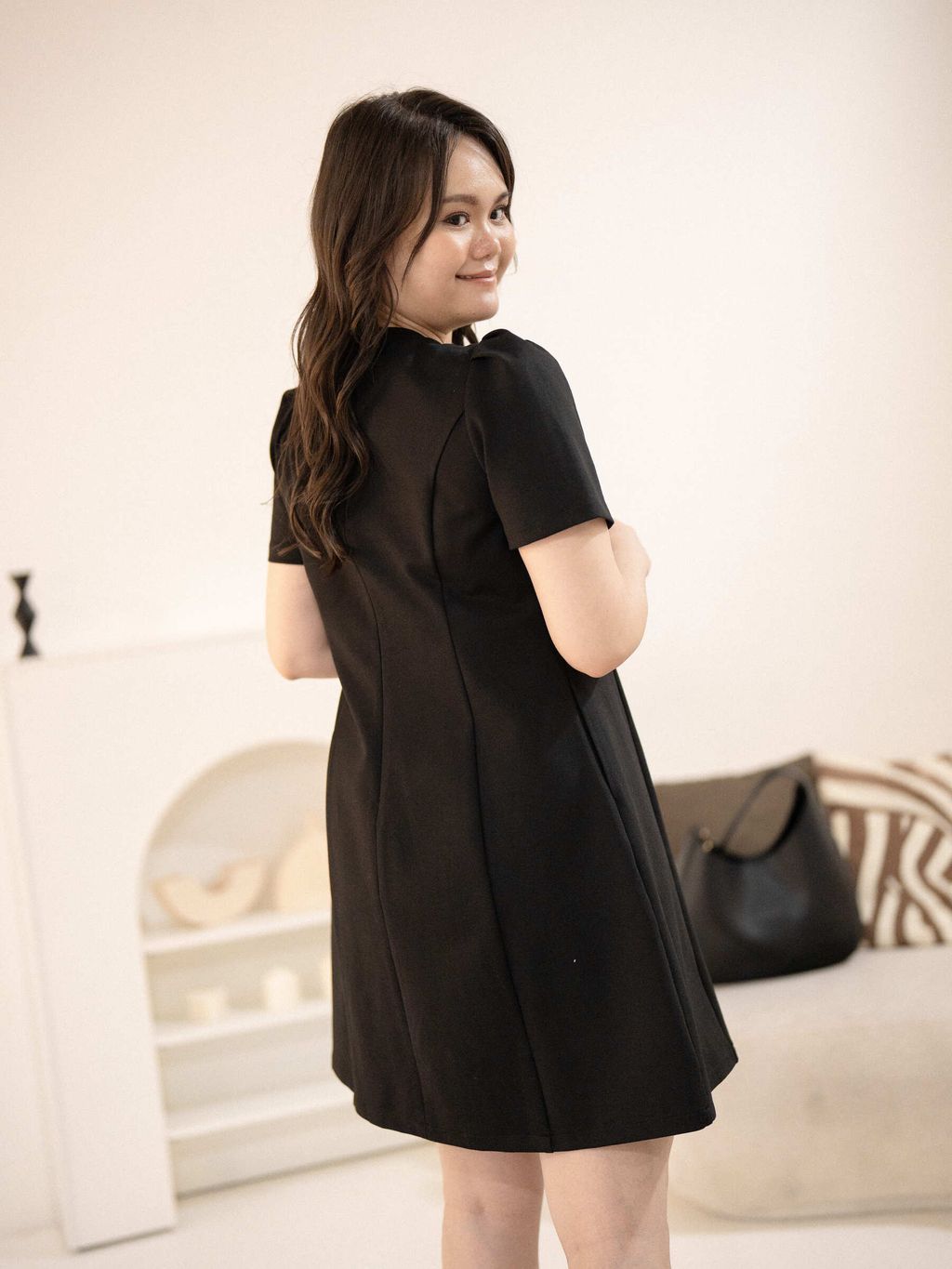 Back view of plus-size model wearing a sleek black dress with puff sleeves