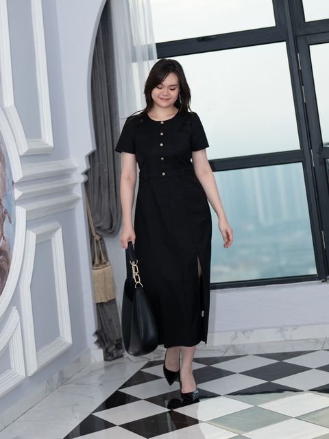Full-body shot of plus-size woman walking confidently in black slit pocket dress.