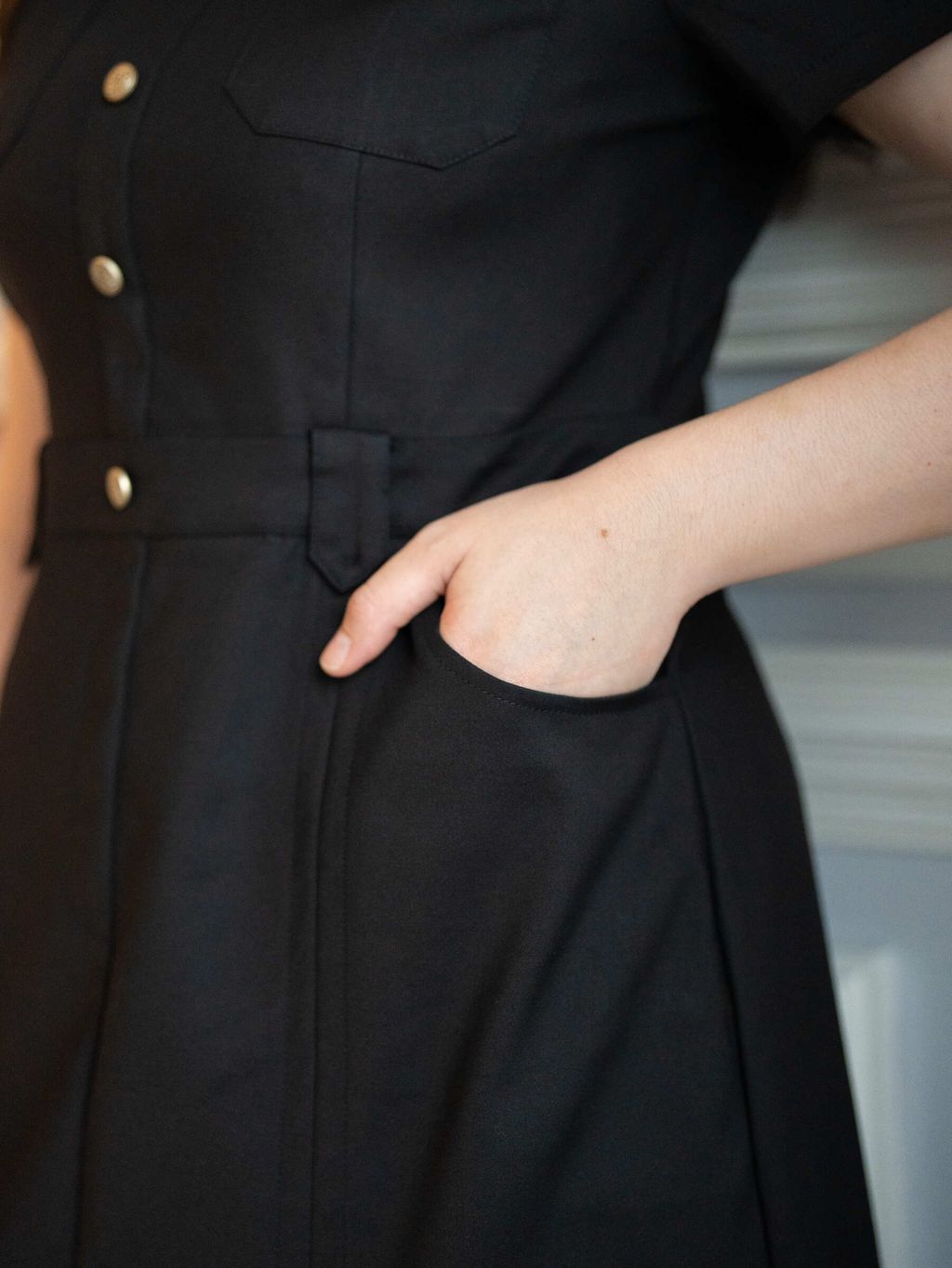 Close-up of black dress pocket with model’s hand inserted.