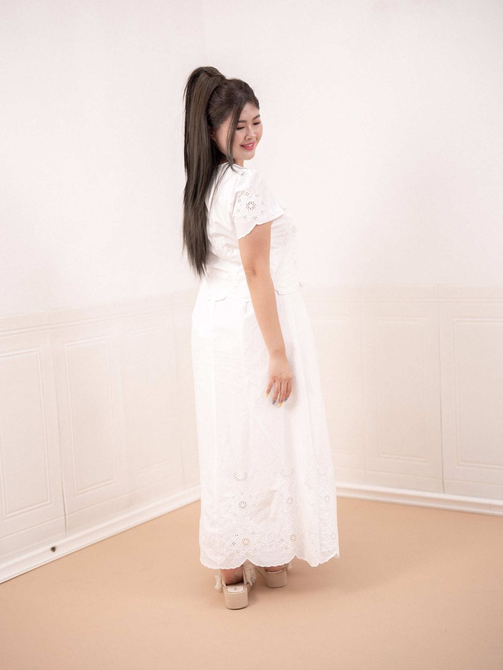 Back view of a white floral eyelet maxi skirt on a curvy woman