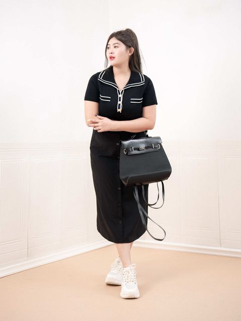 Plus-size model wearing black midi skirt with striped waistband and button-down detail