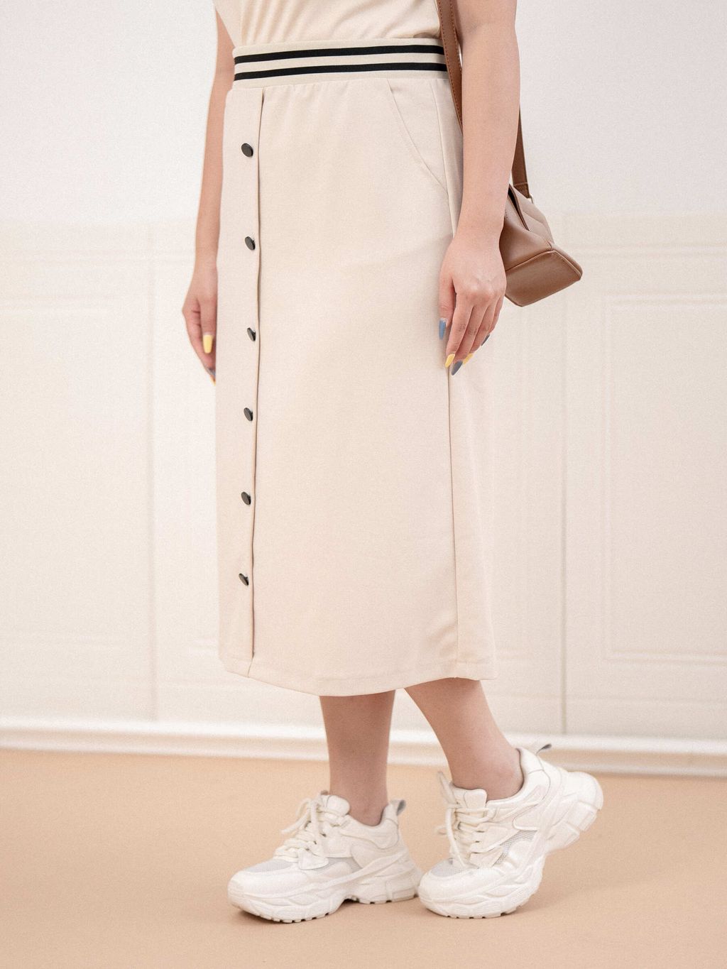 Side view of beige midi skirt showing pocket and clean silhouette
