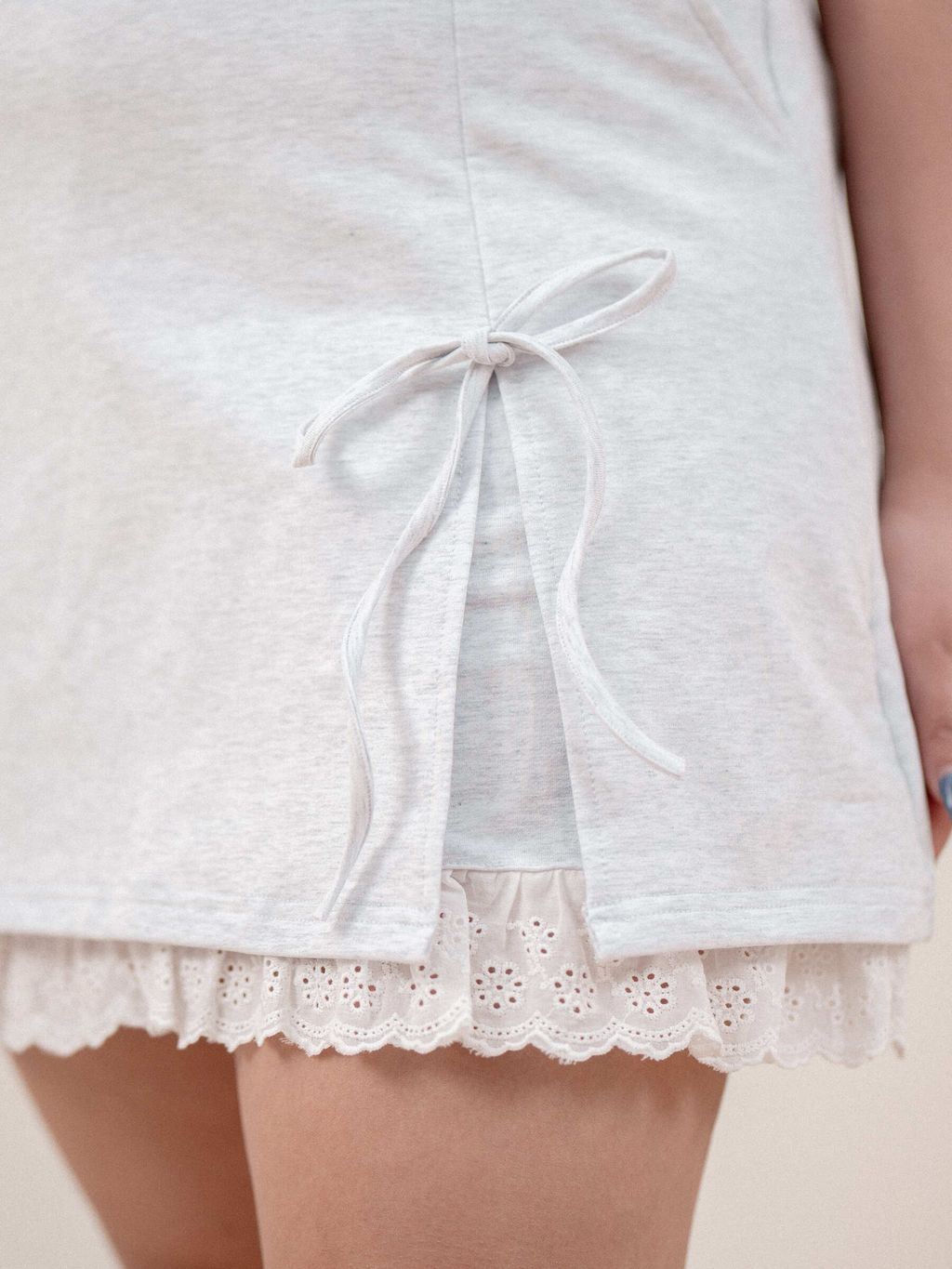 Close-up of mock wrap skirt featuring ribbon tie and lace hem on plus-size model