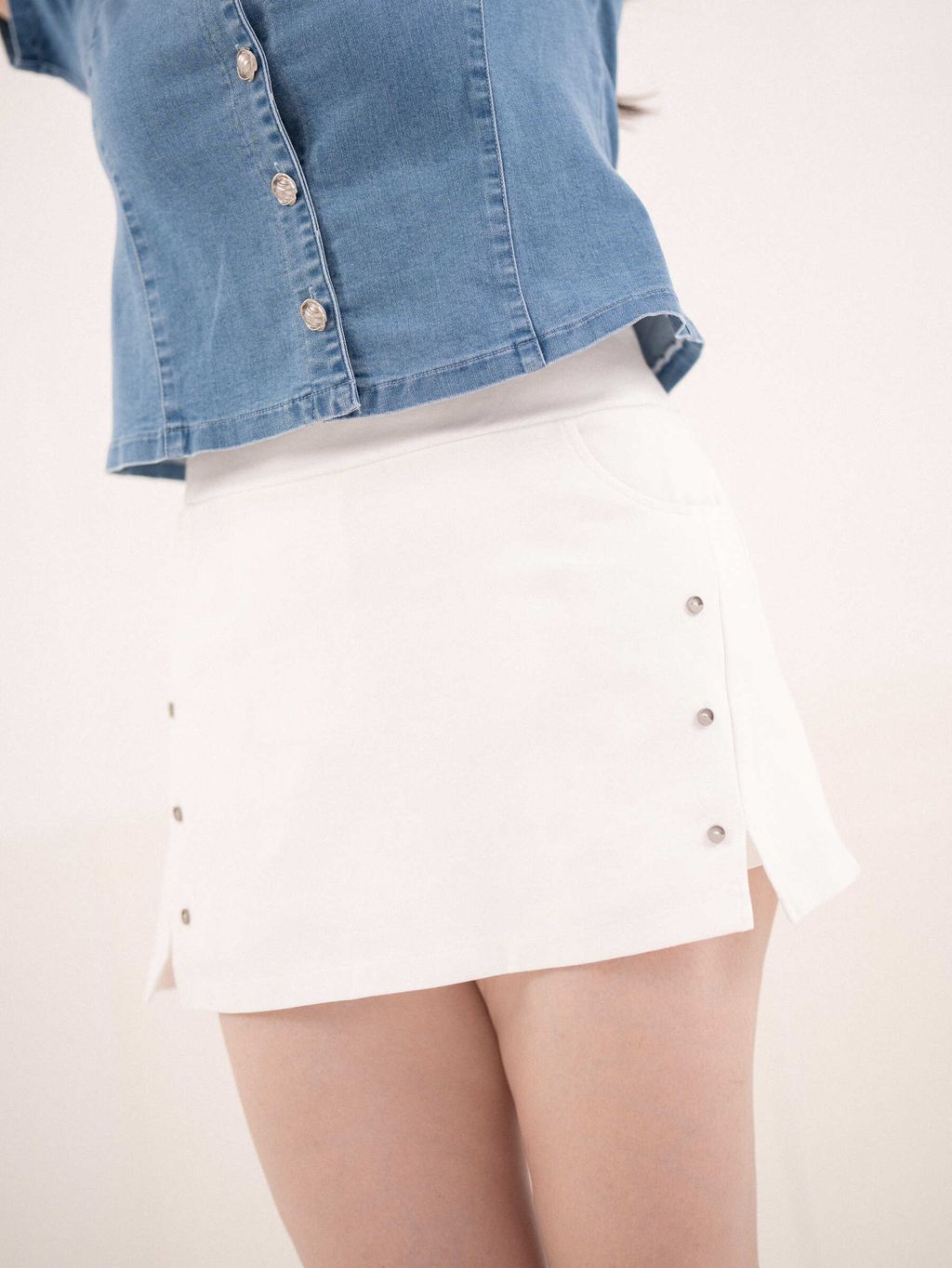 Close-up of white skort with side slit and decorative buttons