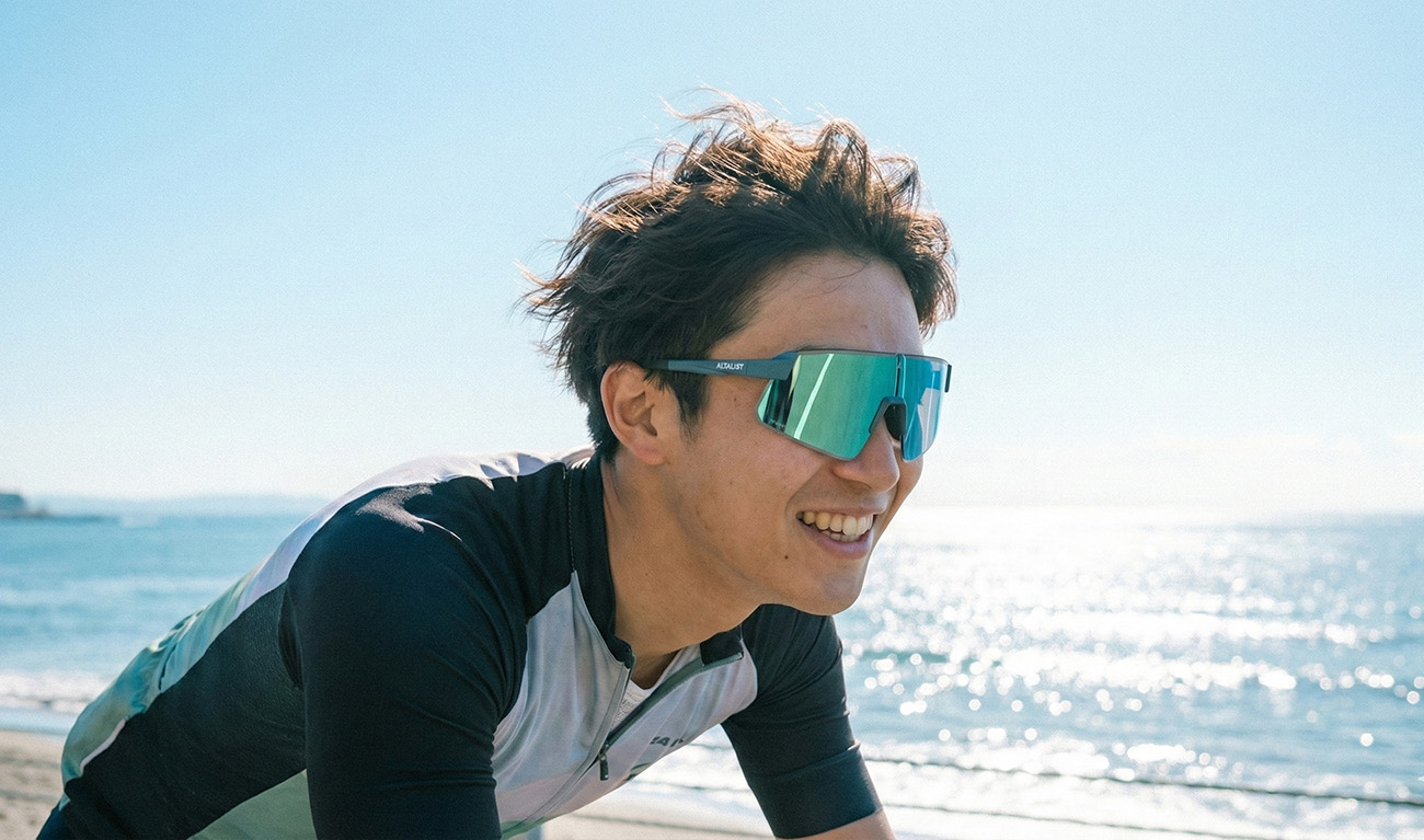 日本年輕男性在湘南海岸騎單車，陽光灑落在臉上，配戴運動眼鏡表情輕鬆