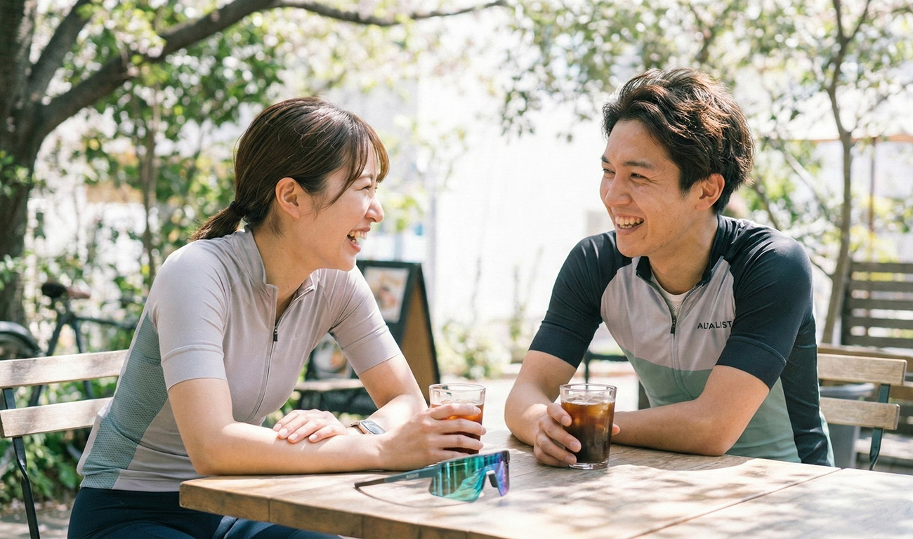 日本情侶穿著騎行服在戶外咖啡廳休息，運動眼鏡隨意地放在木桌上