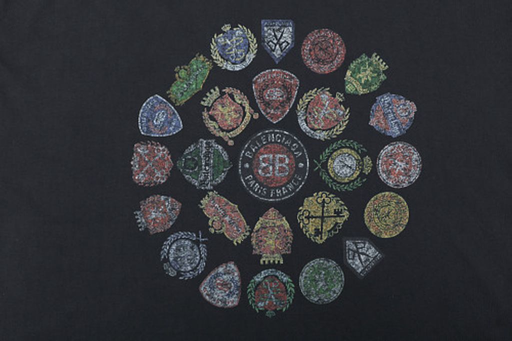 Front and back view of the Balenciaga Vintage Badge Print T-Shirt in washed black, featuring a circular vintage badge graphic on the front, a gothic logo on the back, and a relaxed oversized fit. Available in Singapore and Malaysia.