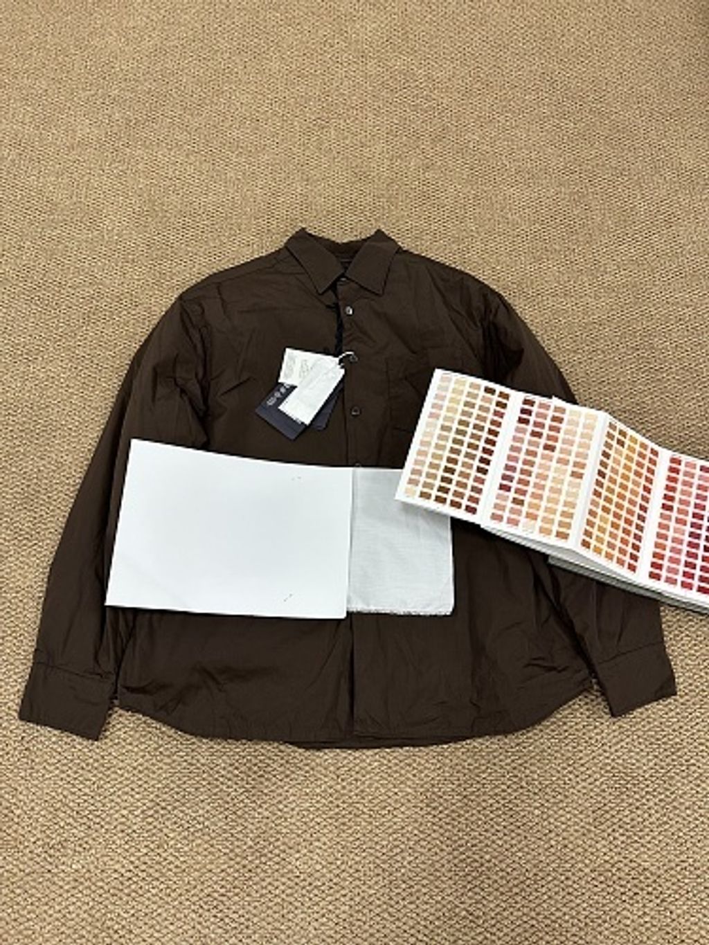 Front and back view of the Prada Inverted Triangle padded overshirt in dark espresso brown, featuring a chest pocket with subtle triangle logo, 200-count pure cotton fabric, and mother-of-pearl buttons. Available in Singapore and Malaysia.