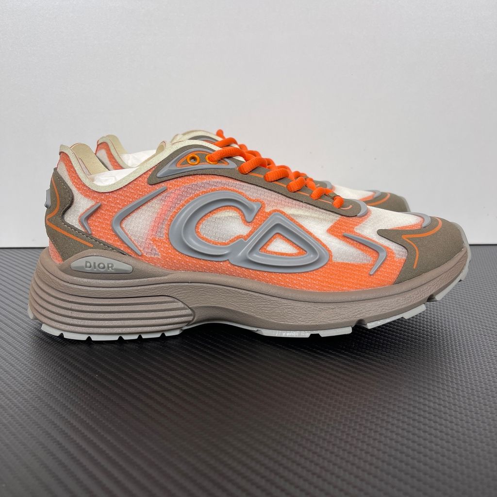 Side profile of the 26SS Dior B30 sneaker in orange and grey, featuring breathable technical mesh, reflective rubber CD30 signatures, and a sculpted lightweight rubber and EVA outsole. Available in Singapore and Malaysia.