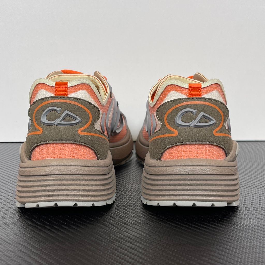 Side profile of the 26SS Dior B30 sneaker in orange and grey, featuring breathable technical mesh, reflective rubber CD30 signatures, and a sculpted lightweight rubber and EVA outsole. Available in Singapore and Malaysia.