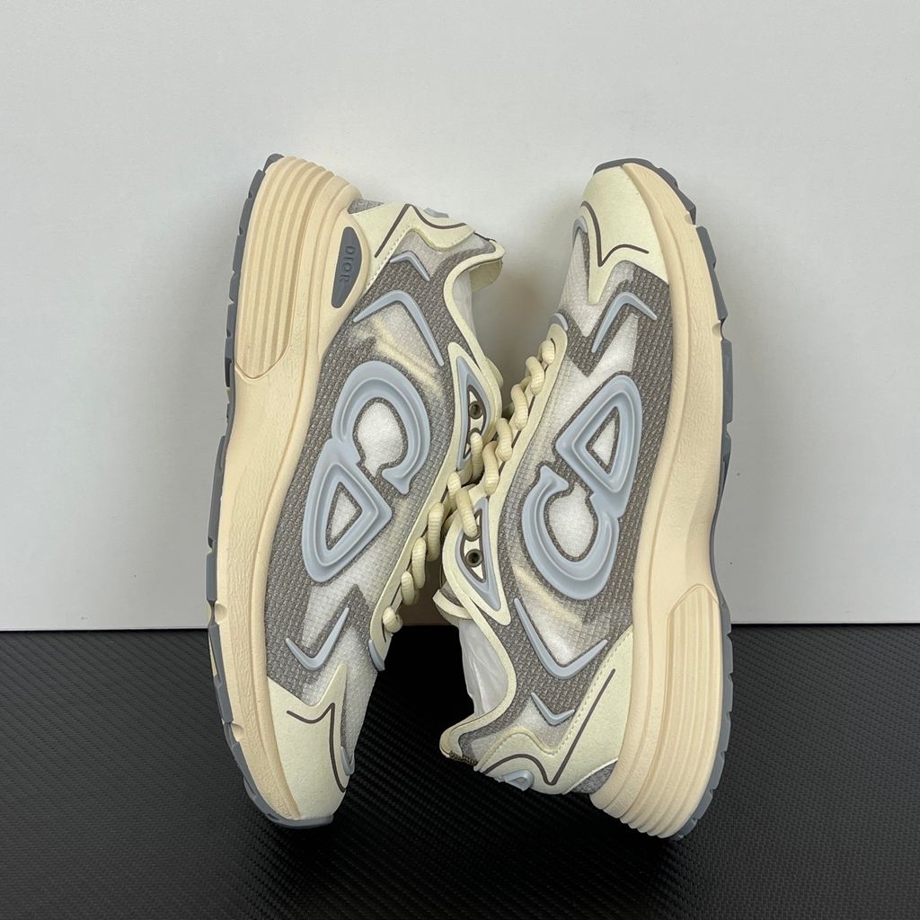 Side profile of the 26SS Dior B30 sneaker in orange and grey, featuring breathable technical mesh, reflective rubber CD30 signatures, and a sculpted lightweight rubber and EVA outsole. Available in Singapore and Malaysia.