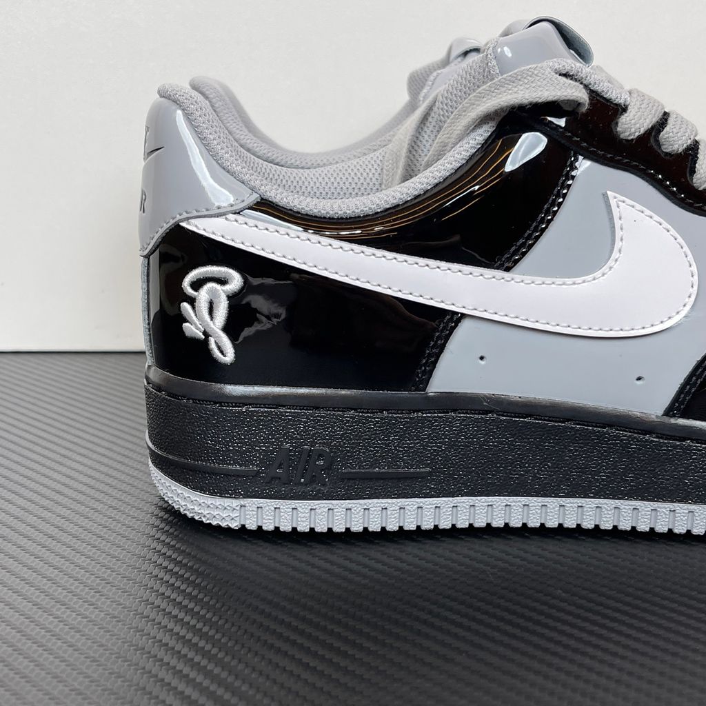 Side profile of the Nike Air Force 1 Low x Syna World sneaker IO9974-010, featuring a premium black leather upper, smoke grey accents, a crisp white Swoosh, and exclusive Syna World branding. Available in Singapore and Malaysia.