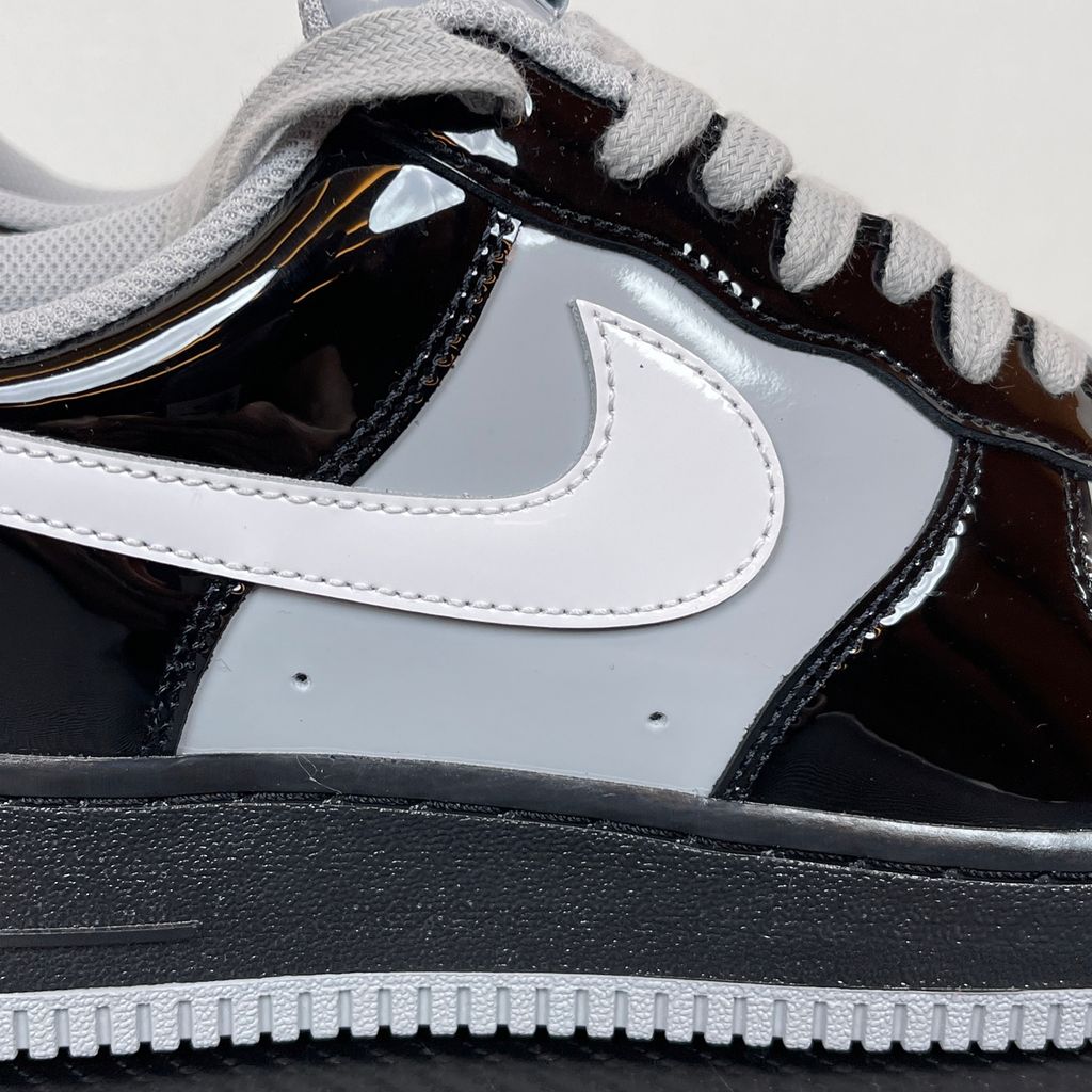 Side profile of the Nike Air Force 1 Low x Syna World sneaker IO9974-010, featuring a premium black leather upper, smoke grey accents, a crisp white Swoosh, and exclusive Syna World branding. Available in Singapore and Malaysia.
