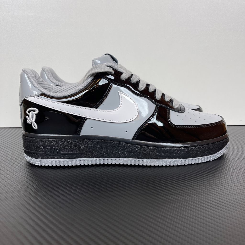 Side profile of the Nike Air Force 1 Low x Syna World sneaker IO9974-010, featuring a premium black leather upper, smoke grey accents, a crisp white Swoosh, and exclusive Syna World branding. Available in Singapore and Malaysia.