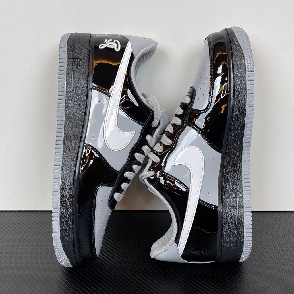 Side profile of the Nike Air Force 1 Low x Syna World sneaker IO9974-010, featuring a premium black leather upper, smoke grey accents, a crisp white Swoosh, and exclusive Syna World branding. Available in Singapore and Malaysia.
