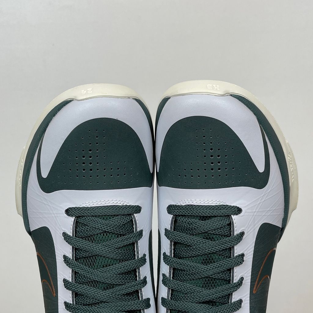 Side profile of the Nike Kobe 5 Protro sneaker CD4991-300 in the EYBL Girls colorway, featuring a dark forest green synthetic upper, a metallic red bronze Swoosh, and the EYBL logo on the tongue. Available in Singapore and Malaysia.