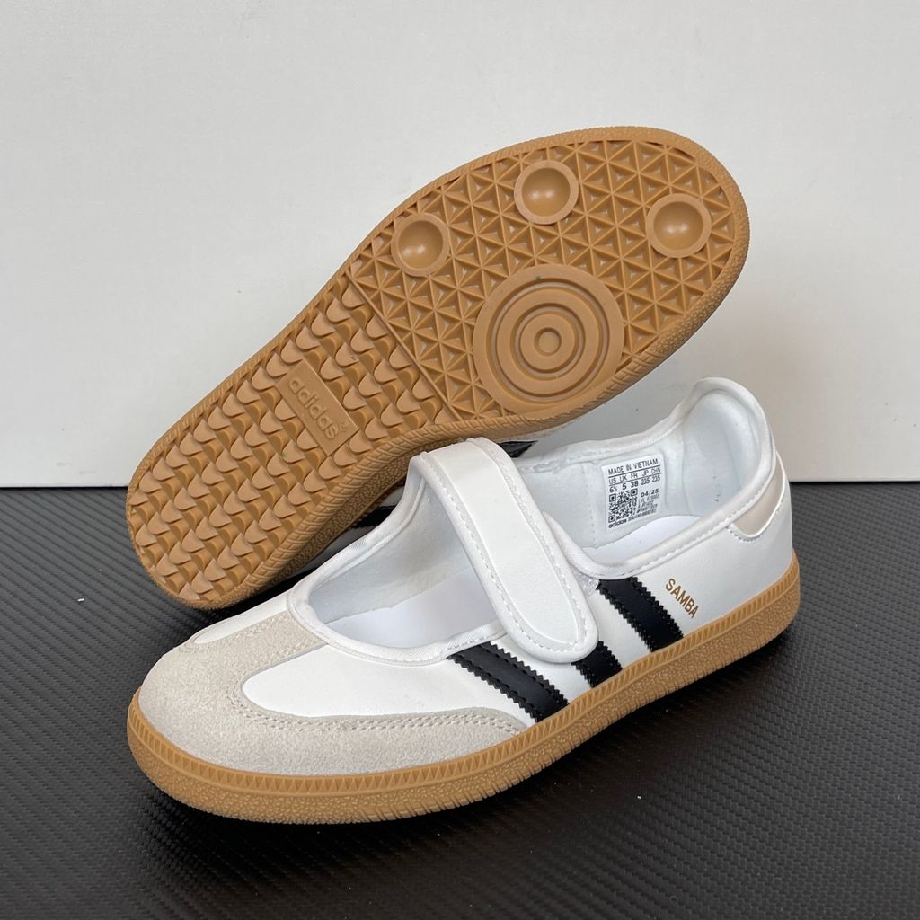 Side profile of the adidas Samba Jane White Black Gum Women's sneaker JR1402, featuring a crisp white leather upper, black serrated 3-Stripes, an adjustable midfoot strap, and a classic gum rubber outsole. Available in Singapore and Malaysia.