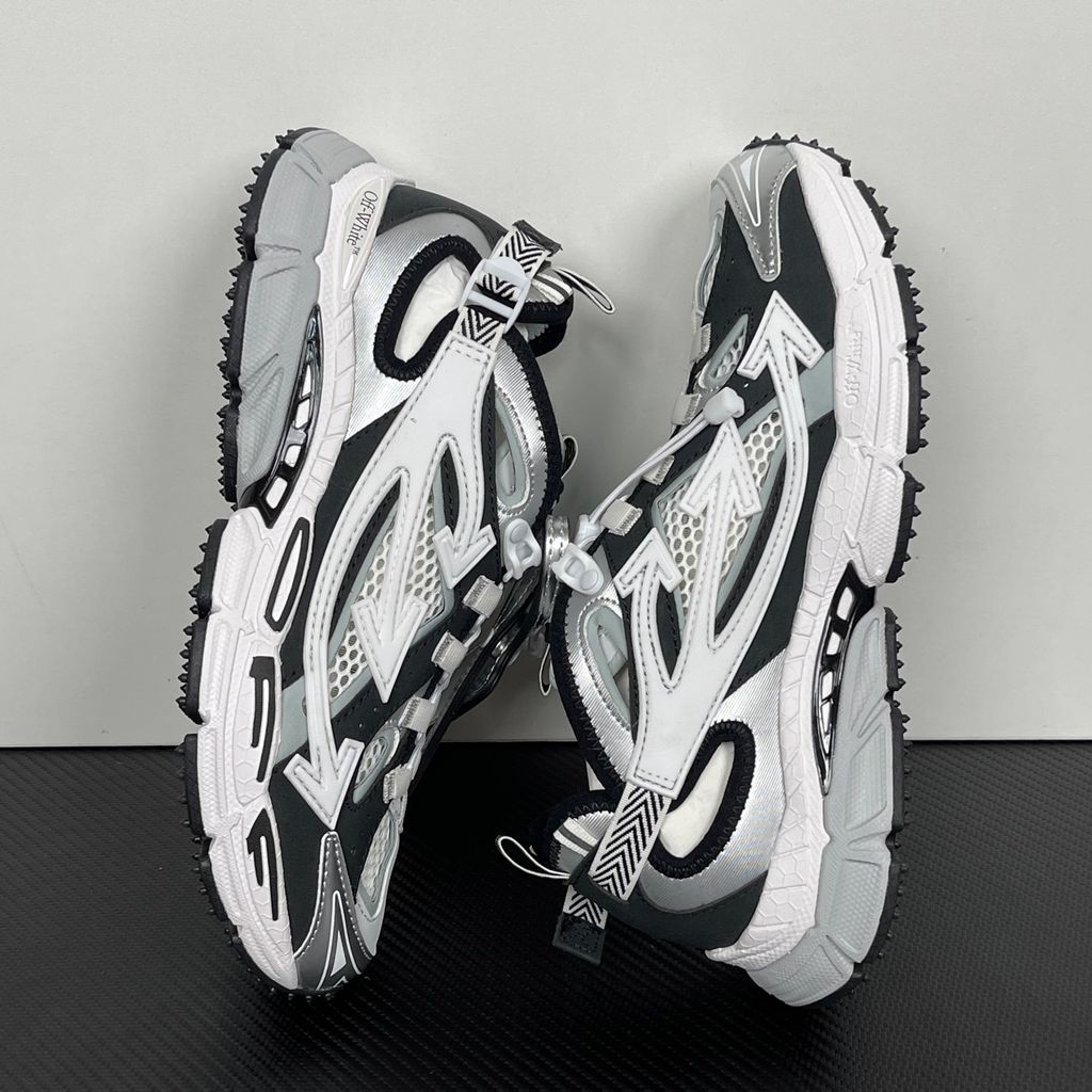 Authentic Off-White Be Right Back (BRB) sneaker in metallic silver, white, and black, featuring a technical mesh base and the signature Off-White Arrow logo on the lateral side, SKU OMIA29SS26FAB0017210.